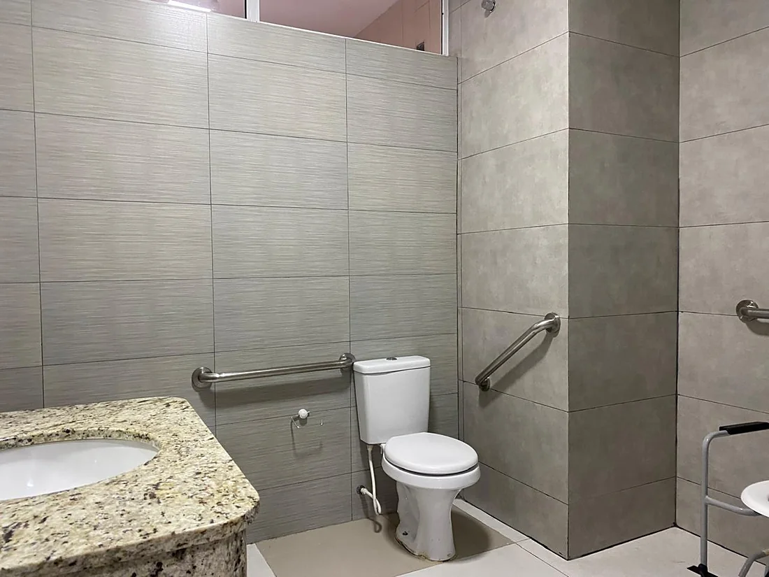 Banheiro adaptado com barras de apoio ao lado do vaso e no box