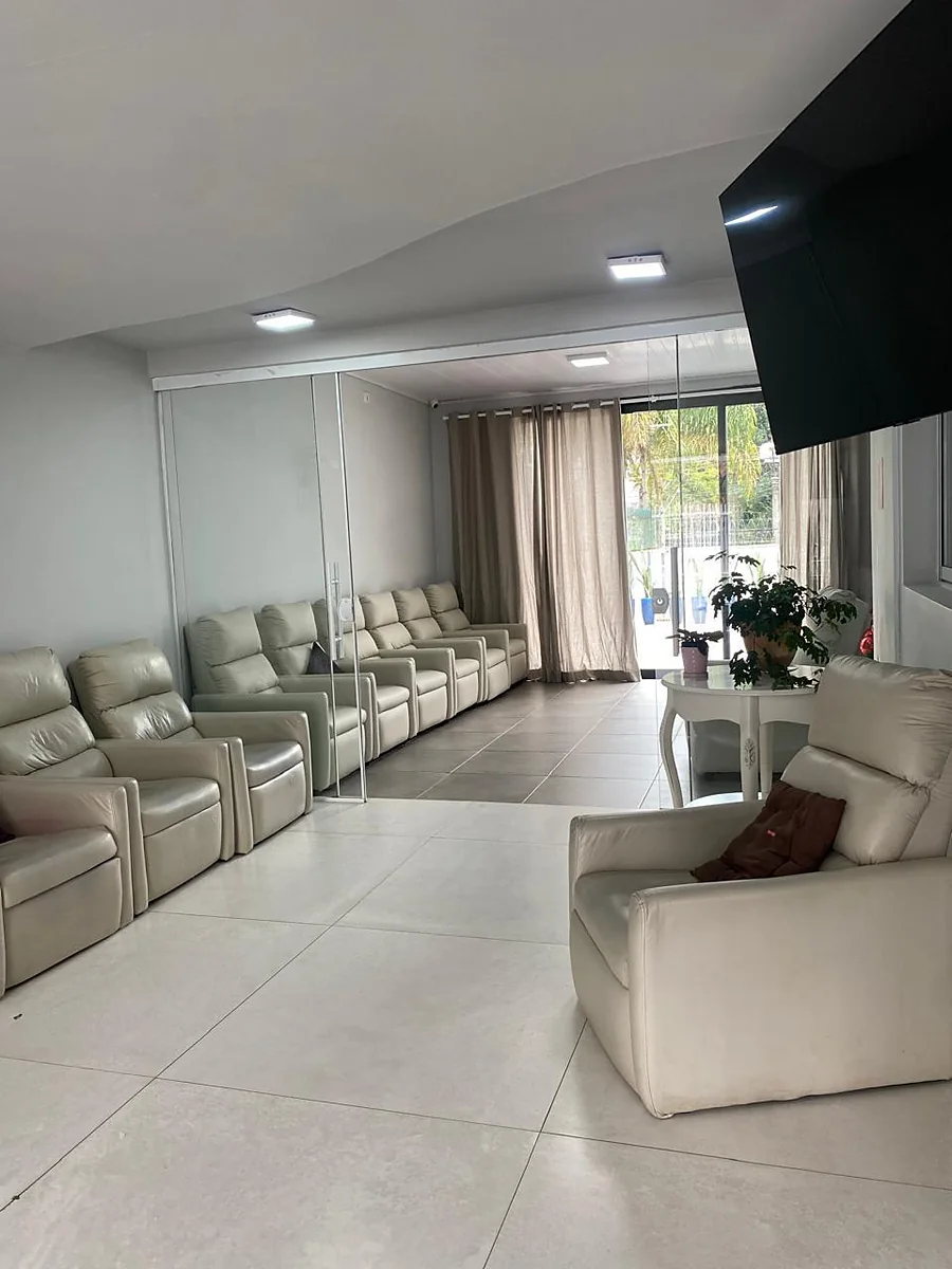 Sala de convivência com poltronas reclináveis e porta de vidro para a área externa