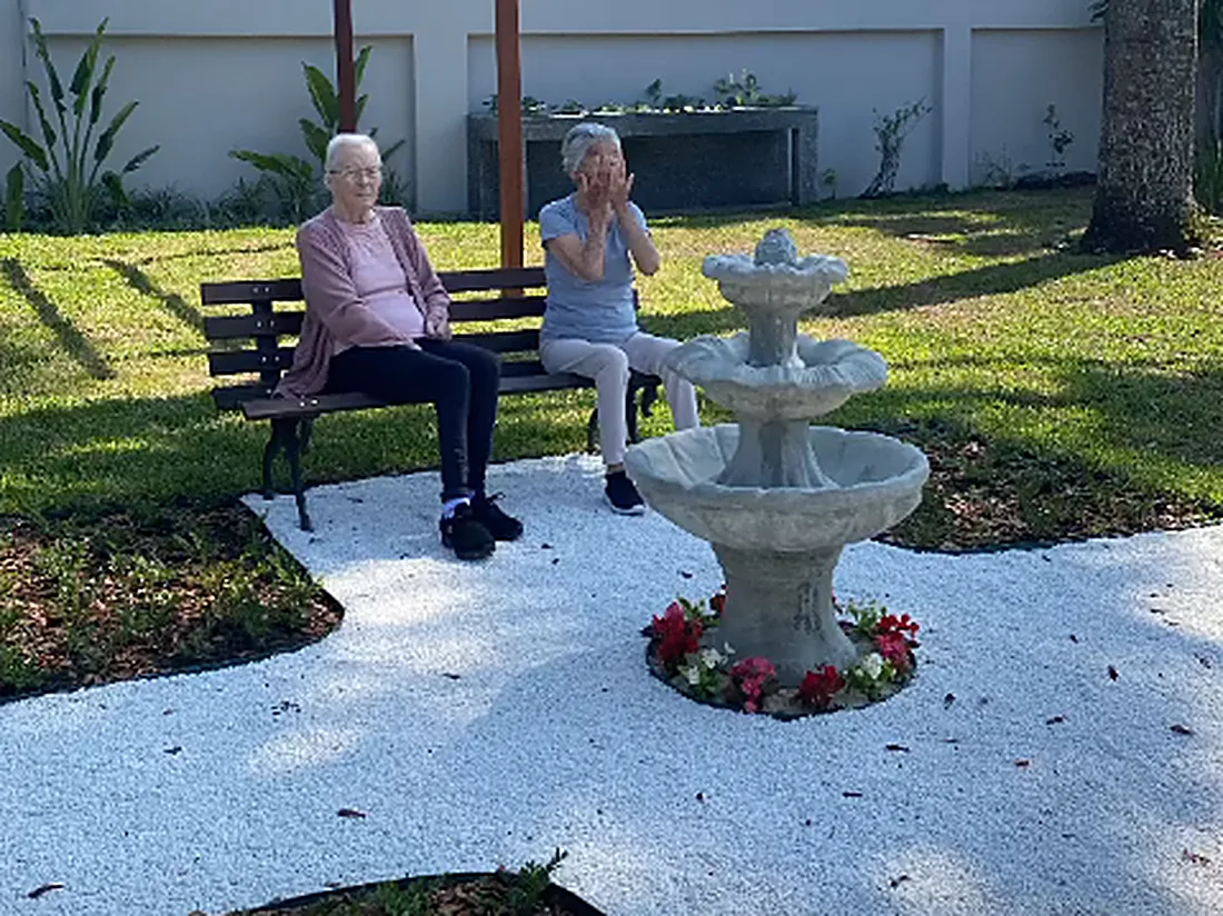 Moradoras sentadas em banco no jardim, ao lado do chafariz