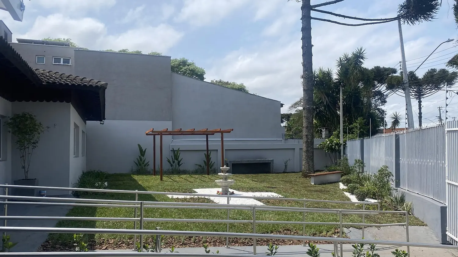 Jardim da Laguna House, com araucária, pergolado de madeira e chafariz, visto da rampa de acesso