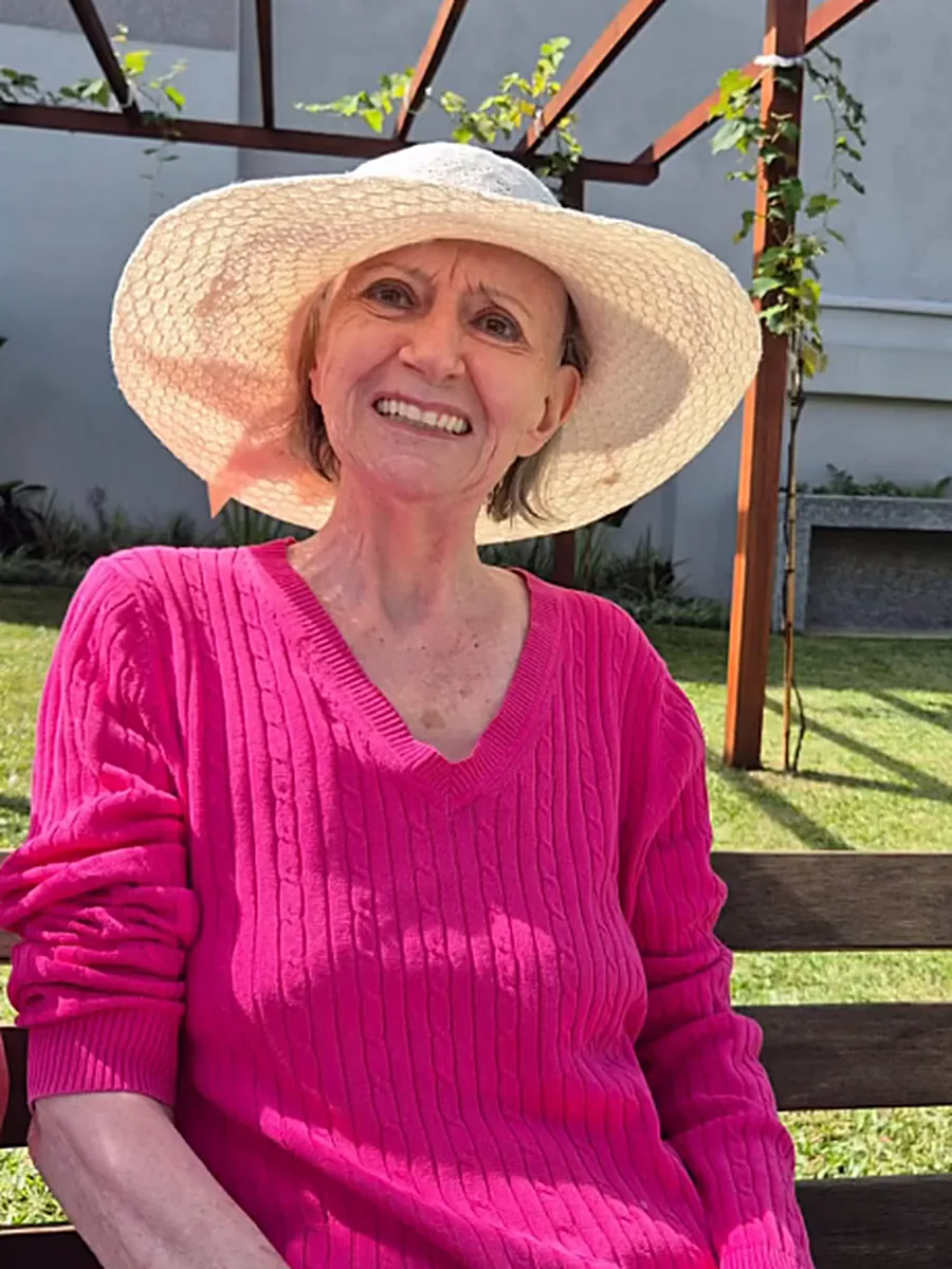 Moradora sorrindo no jardim da casa